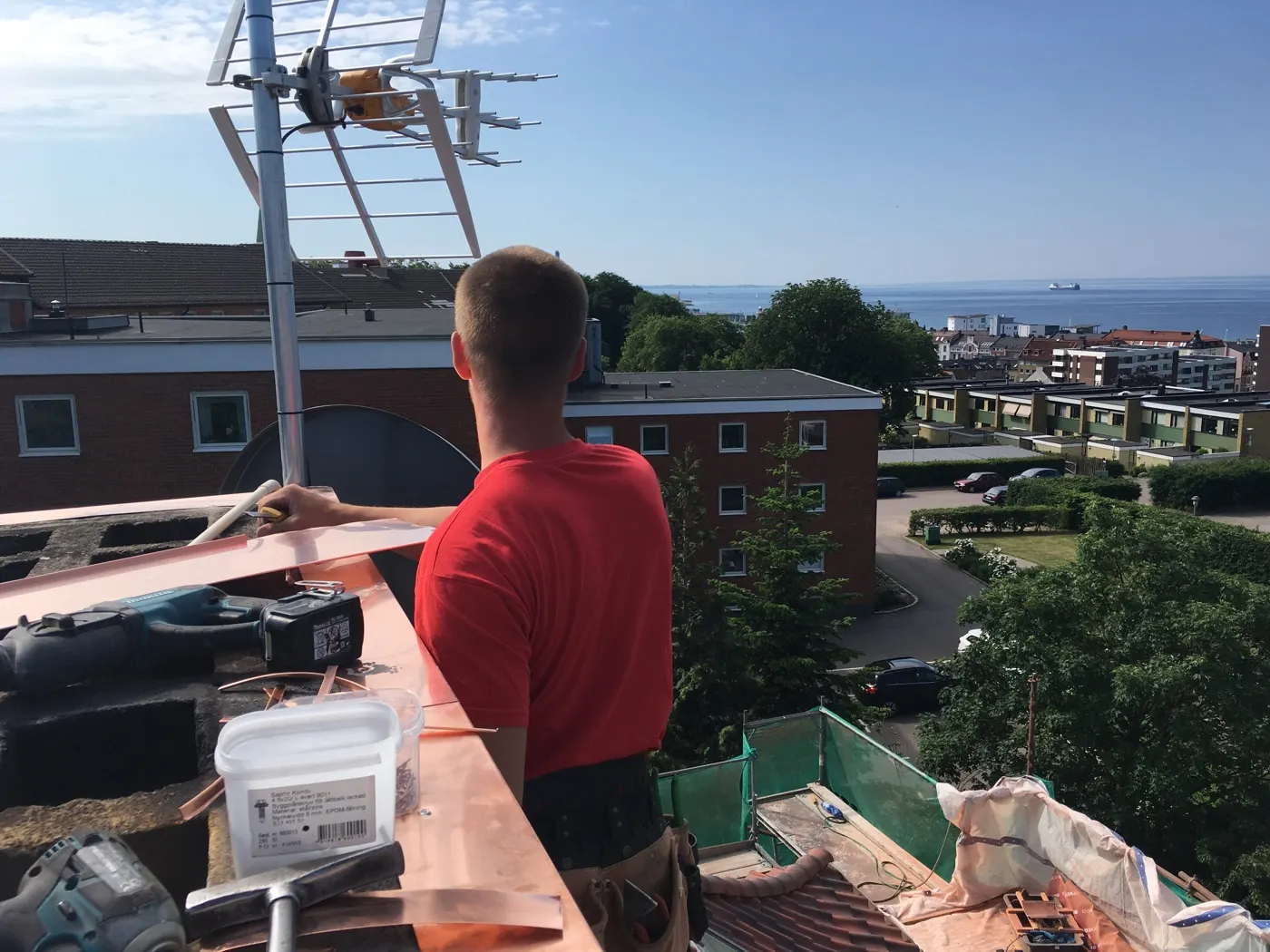 Plåtslagare böjer kopparplåt på ställningen, med utsikt över sundet. Bild 6 av 6