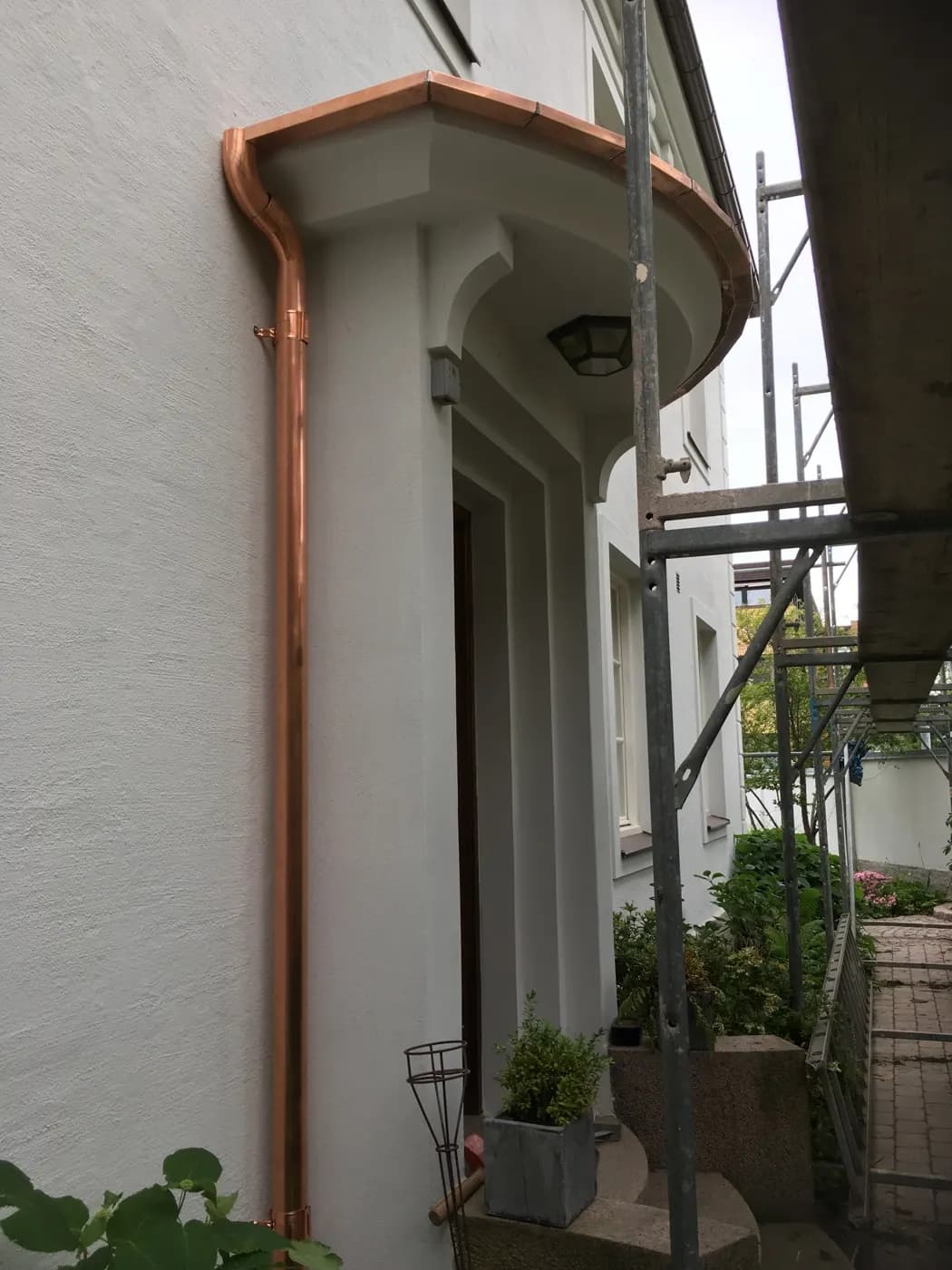 Stuprör i koppar längs den vitputsade fasaden. Bild 5 av 6