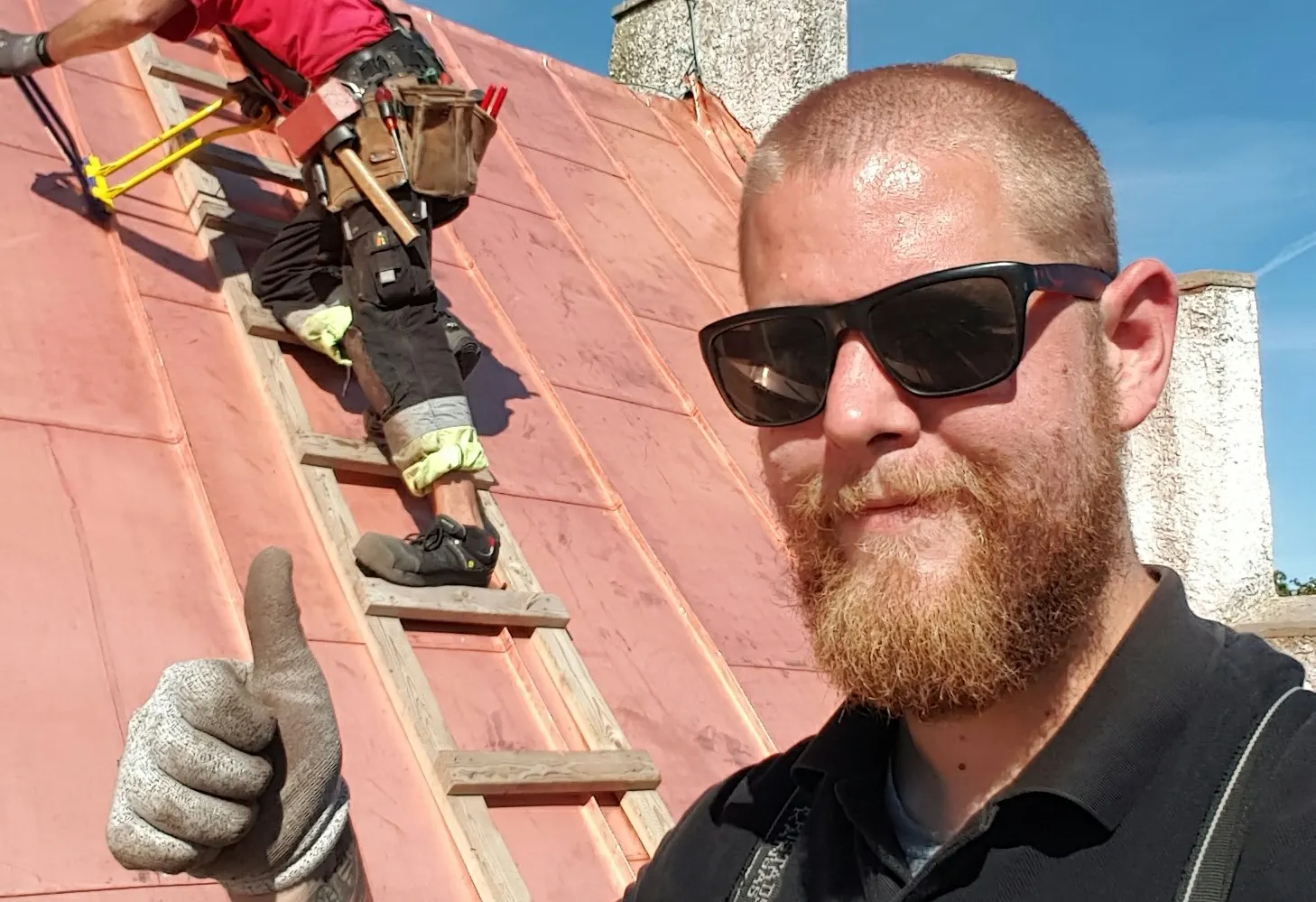 Plåtslagare på det nylagda koppartaket i solsken. Bild 3 av 7
