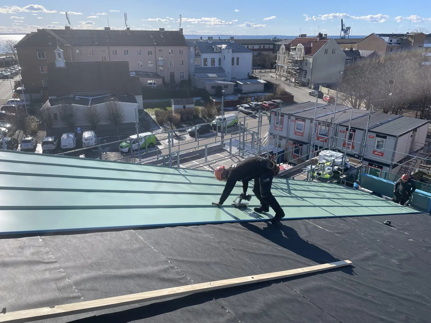 Plåtslagare lägger ärggröna skivor på takfallet över skolgården. Bild 1 av 7