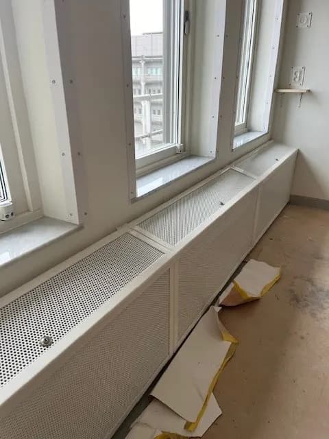 Elementskydd med perforerad front löpande längs fönsterväggen. Bild 2 av 7