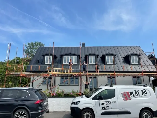 Huset framifrån med färdigt tak och kupor, personal på ställningen. Bild 4 av 62