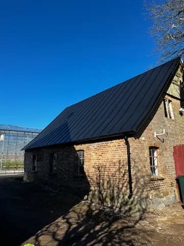 Mörkt bandtäckt tak på en gammal tegellänga. Bild 8 av 62