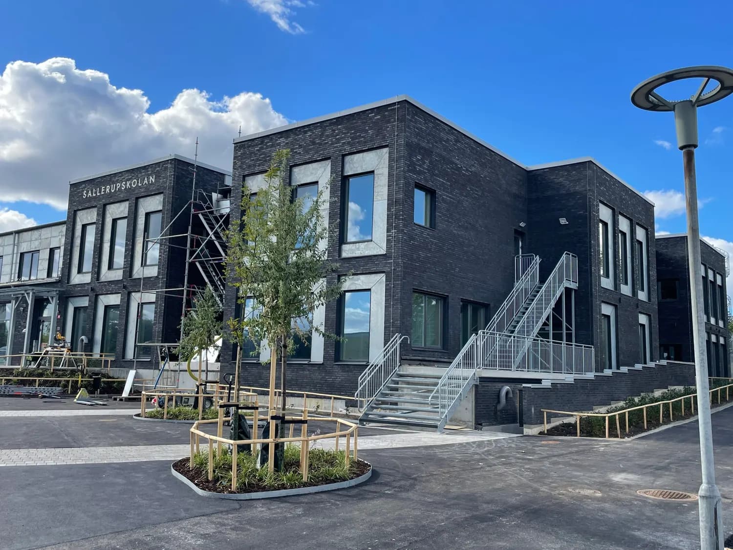 Byggnadens hörn i mörkt tegel, med utrymningstrappa i stål. Bild 3 av 19