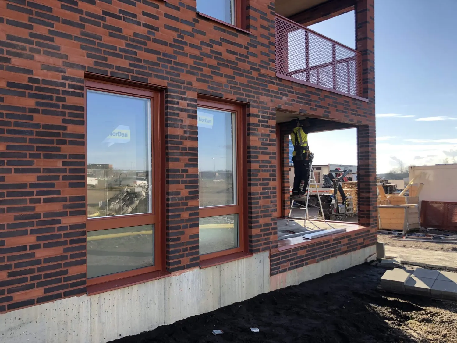 Plåtslagare monterar fönsterbleck i tegelfasaden. Bild 5 av 8