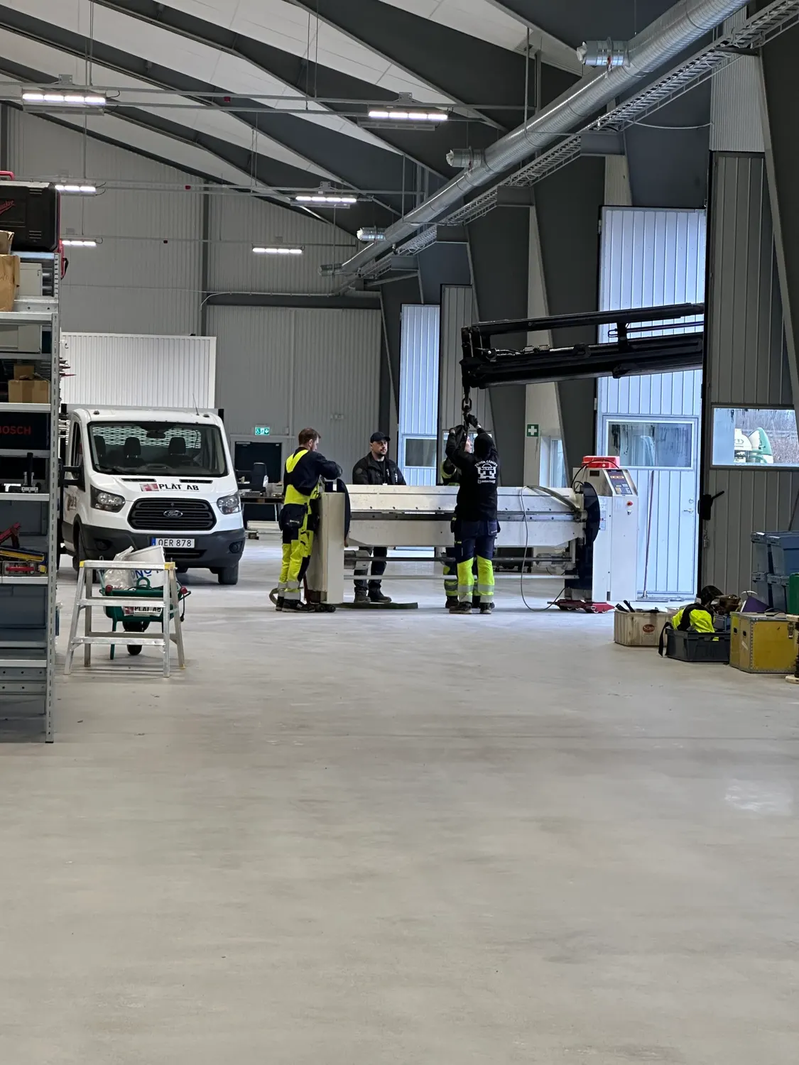 Plåtslagare som riggar en maskin på plats i den nya verkstaden. Bild 11 av 16