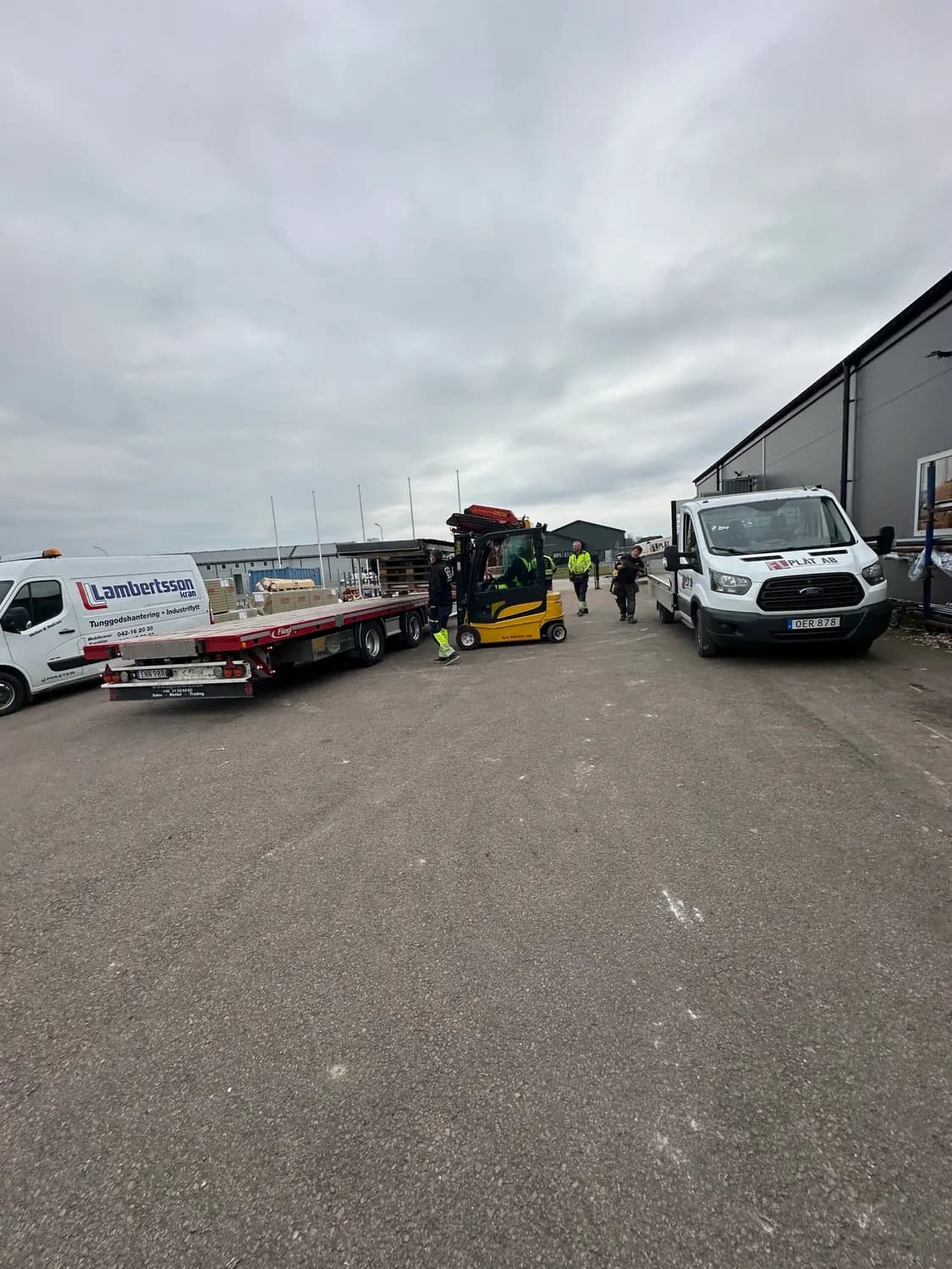 Flyttdag på gården med truck, lastbilar och personal i arbete. Bild 14 av 16