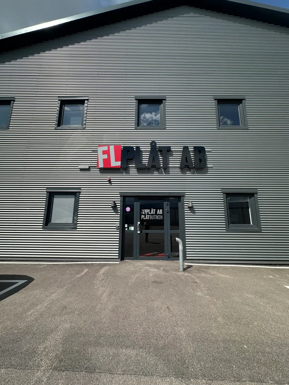 Entrén rakt framifrån, med skylten och Plåtbutikens skyltfönster. Bild 2 av 16
