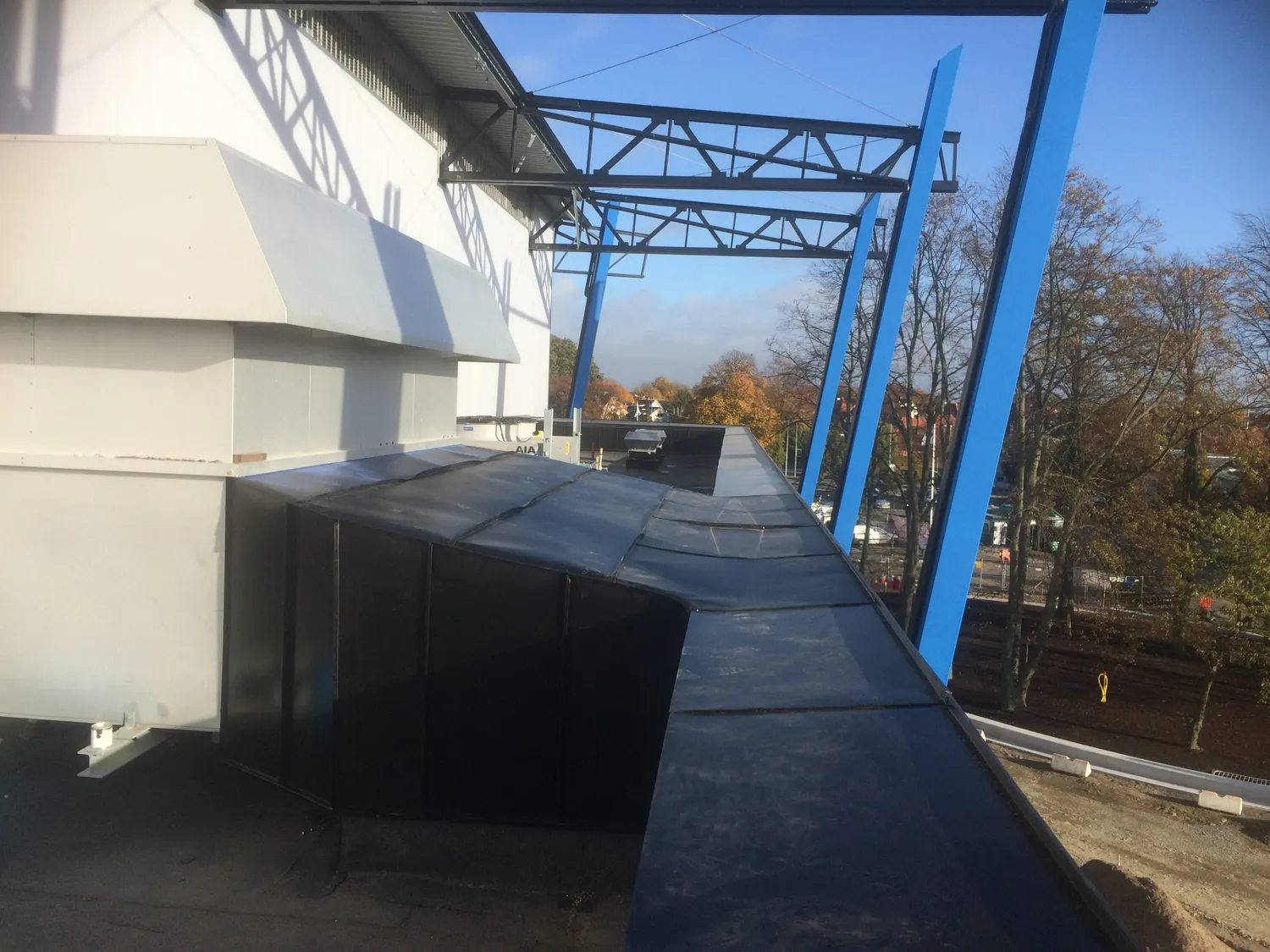 Krönbeslag i mörk plåt monterat på en mur vid arenabygget. Bild 1 av 2