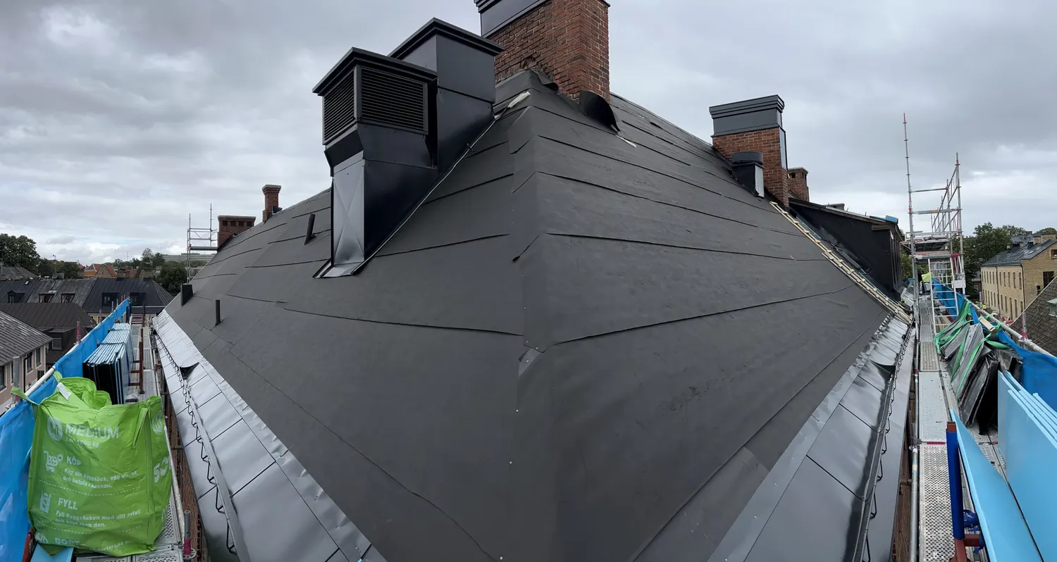 Skorsten och ventilhuv inklädda i svart plåt på det nya taket. Bild 5 av 11