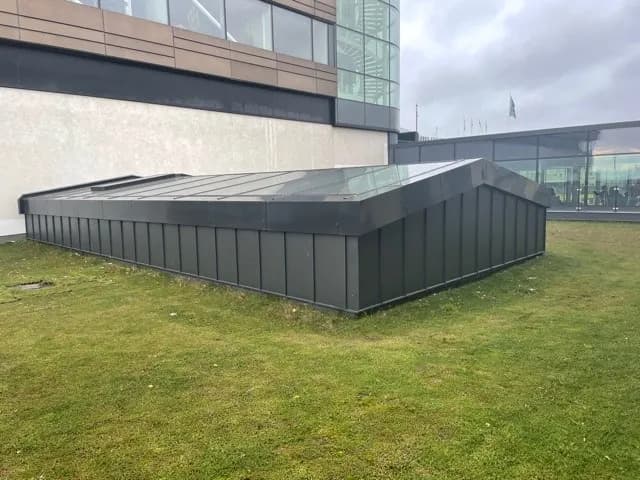 Den plåtklädda lågbyggnaden på gräsmattan intill huvudbyggnaden. Bild 10 av 14