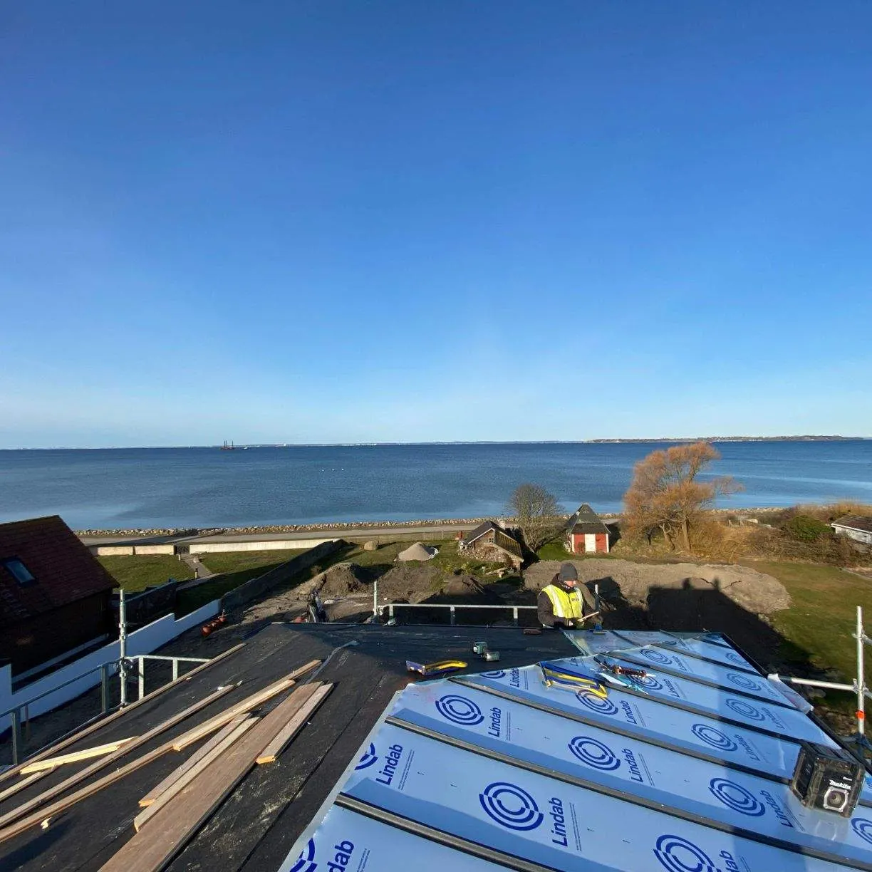 Underlagsduk och plåtbuntar på taket inför läggningen. Bild 19 av 62