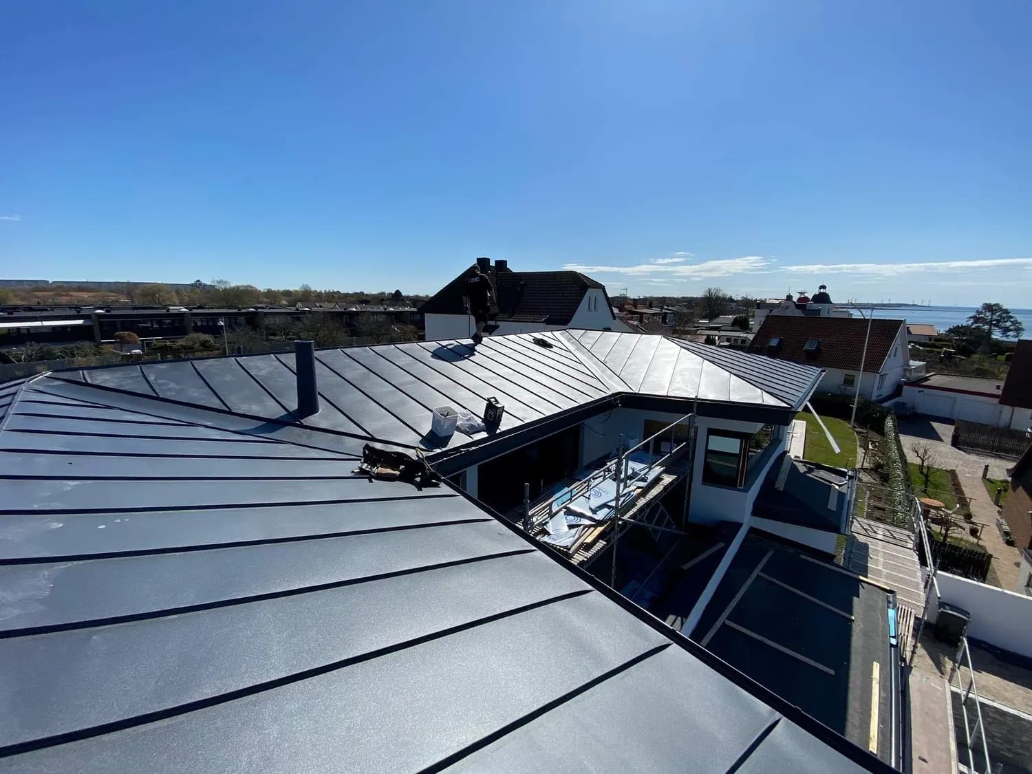 Plåtslagare på taket med utsikt över kustsamhället. Bild 17 av 62