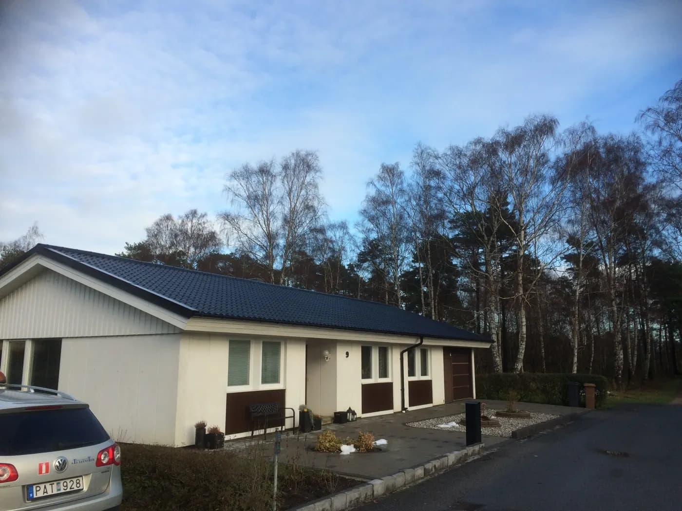 Enplanshus med mörkt plåttak i skogsbrynet. Bild 36 av 62