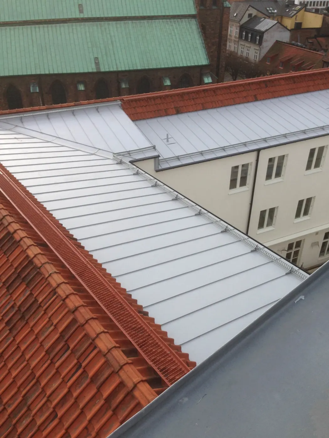 Ljus bandtäckning möter tegeltak vid en ränndal. Bild 38 av 62