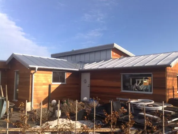 Tillbyggnaden utifrån, med plåttak och trädetaljer. Bild 43 av 62