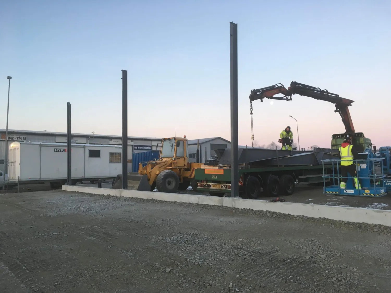 Första pelarna resta på grunden, kranbil bredvid. Bild 11 av 23