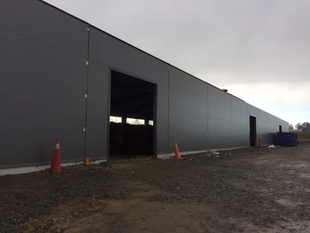 Väggarna klädda i grå plåt, med porten öppen mot hallen. Bild 18 av 23