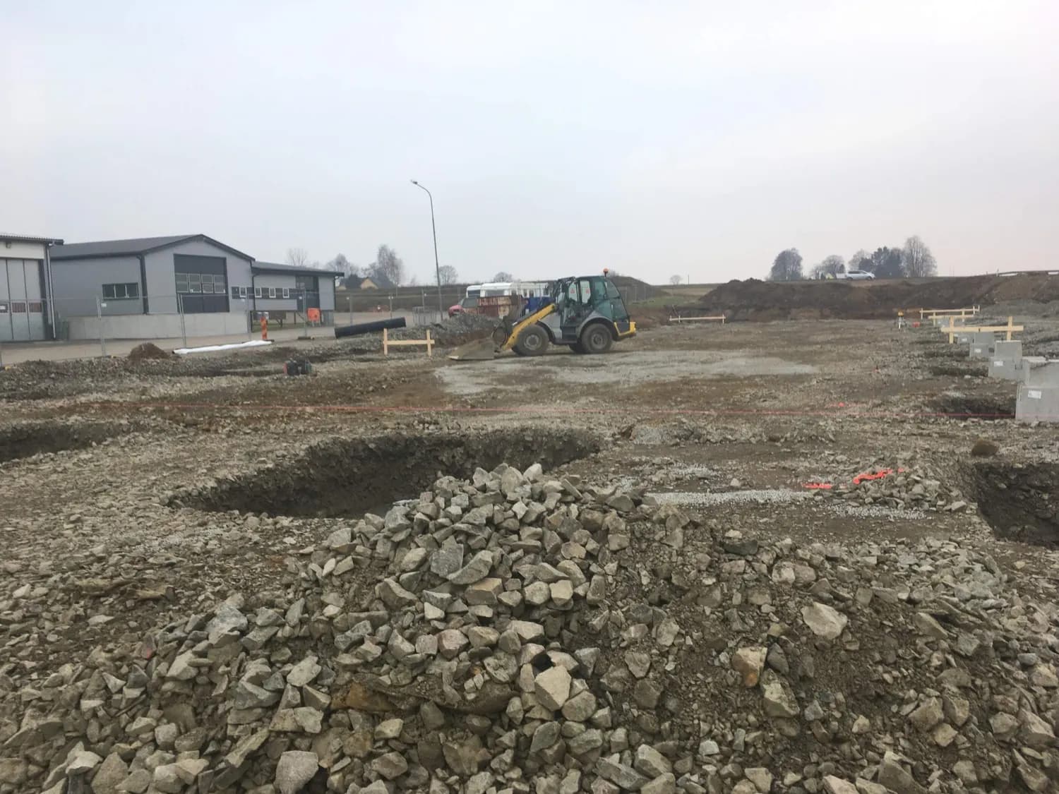 Schaktarbetet igång med hjullastare och urgrävda gropar. Bild 4 av 23
