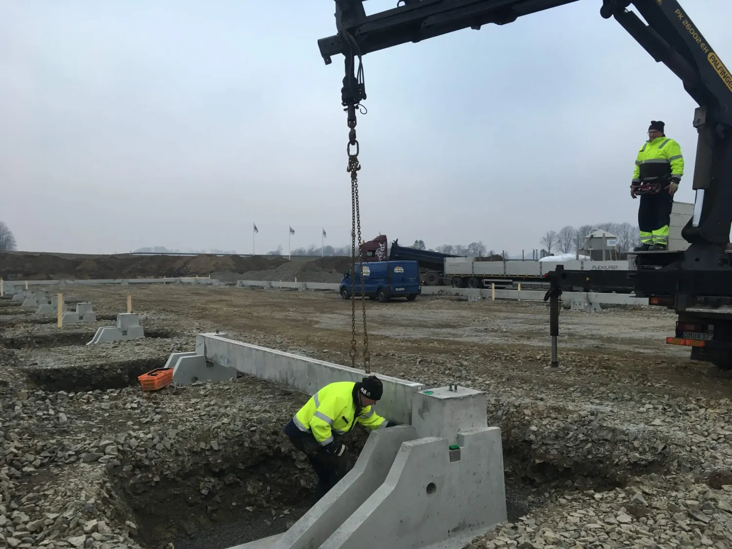 Betongsockel lyfts på plats med kranbil. Bild 5 av 23