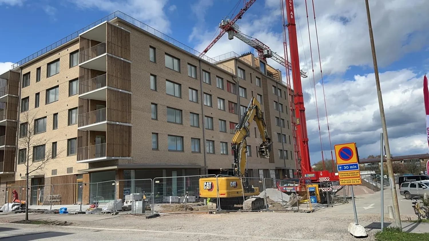 Byggnaden under uppförande med tornkran och grävmaskin framför. Bild 4 av 6
