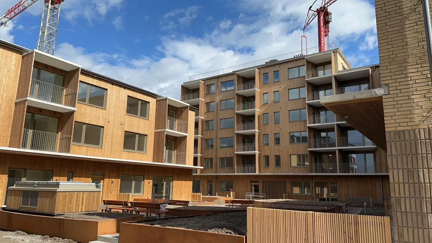 Gårdssidan med balkonger i flera våningar och träpanel i förgrunden. Bild 5 av 6