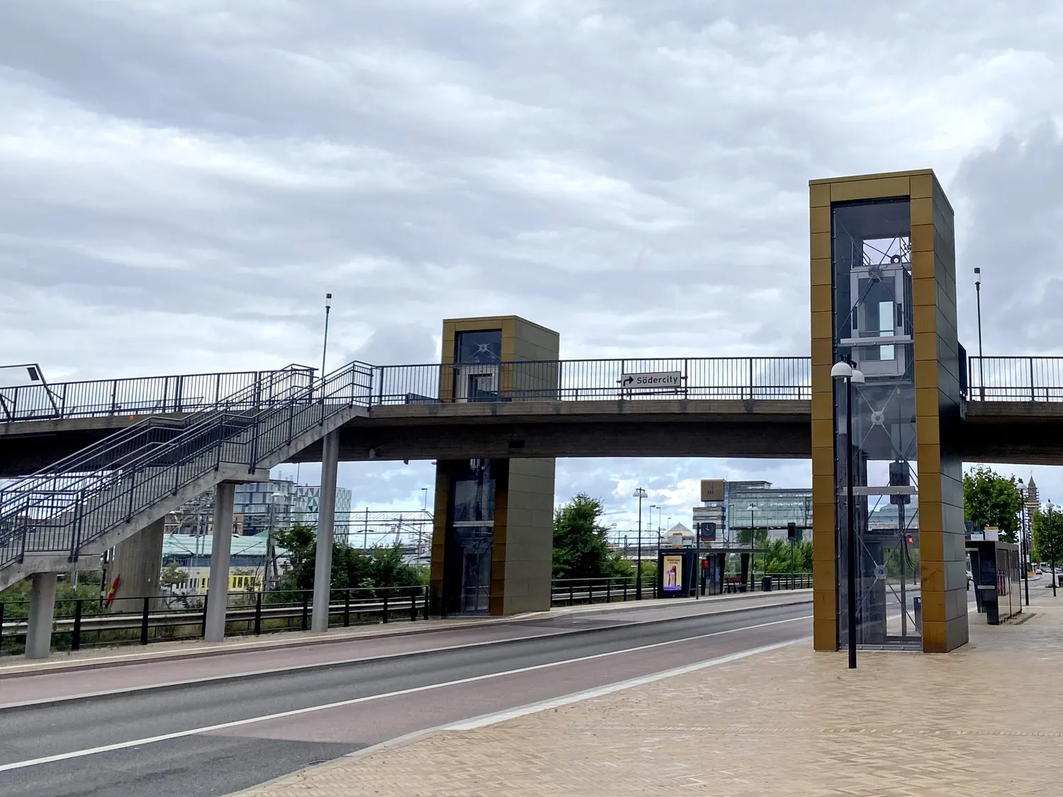 Gångbron över gatan med hisstornet i mässingsfärgad plåt. Bild 1 av 14