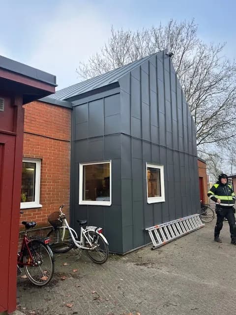 Den plåtklädda tillbyggnaden framifrån, med cyklar och personal utanför. Bild 5 av 9