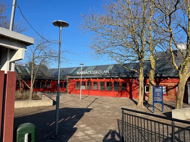 Skolans entré med namnskylt, sedd över skolgården en vinterdag. Bild 9 av 9