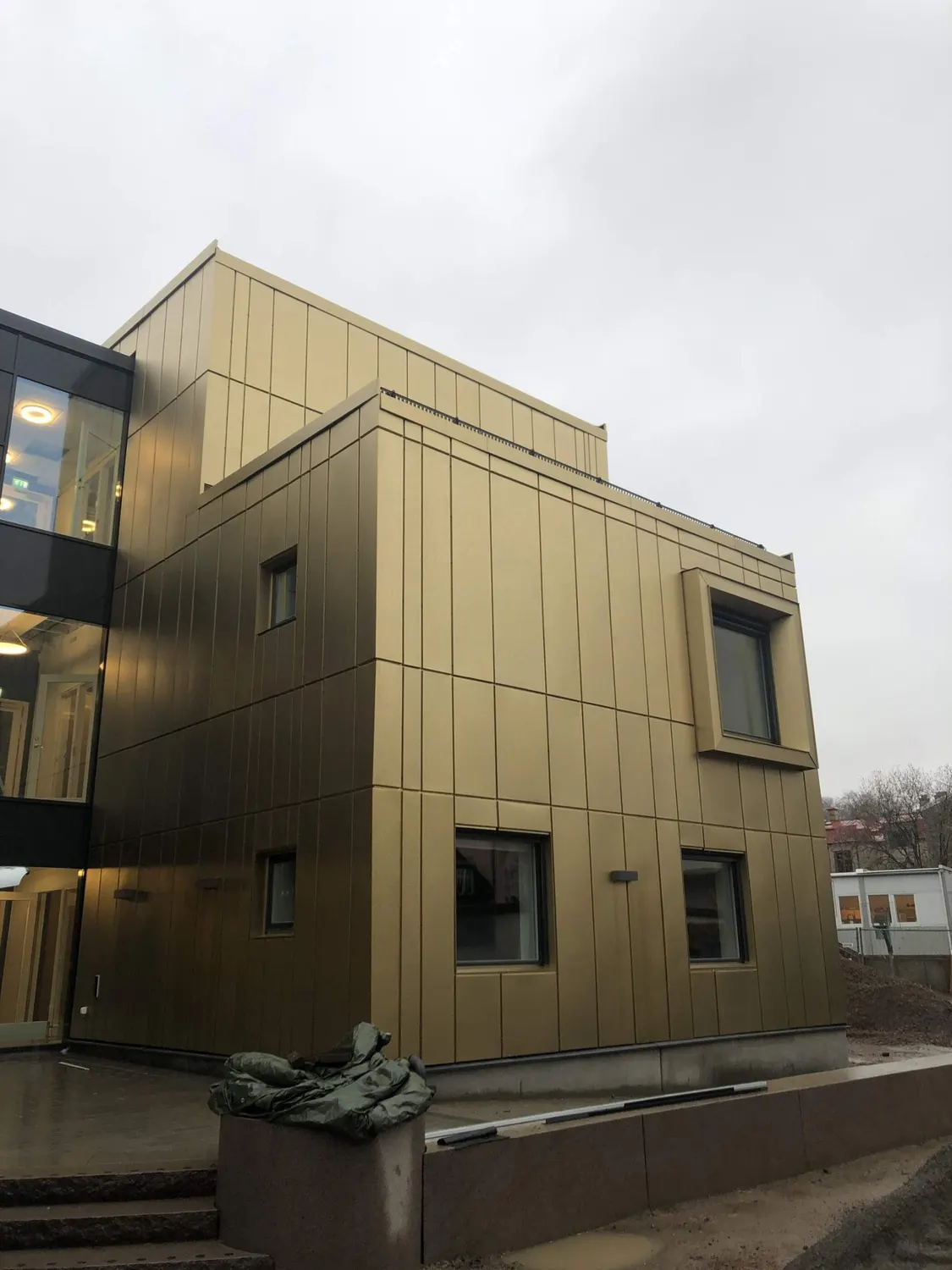 Fasaden i kvällsljus intill det glasade trapphuset. Bild 10 av 11