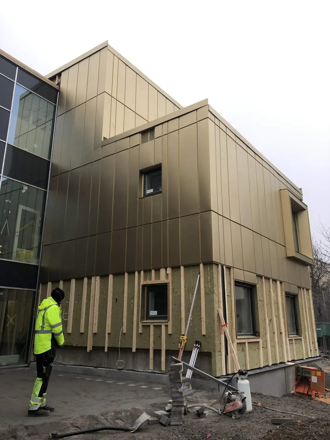 Plåtslagare framför den halvfärdiga fasaden vid glaspartiet. Bild 6 av 11
