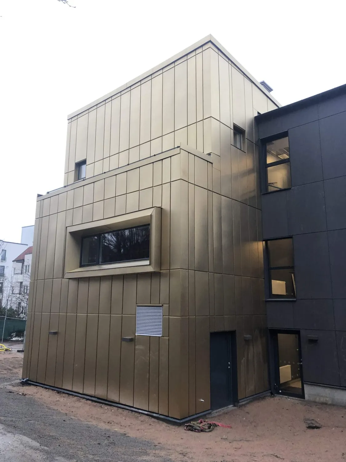 Den färdiga fasaden möter den mörka lägre byggnadsdelen. Bild 4 av 11