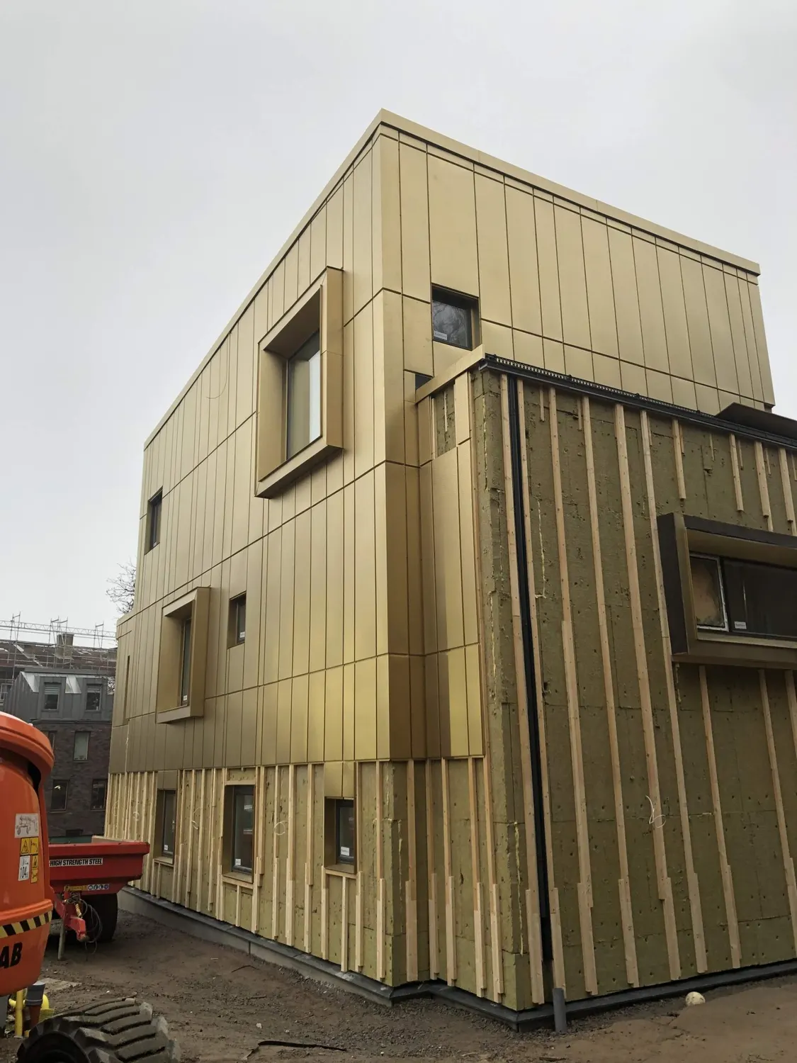 Hörnet med utskjutande fönsternischer i mässingsfärgad plåt. Bild 3 av 11
