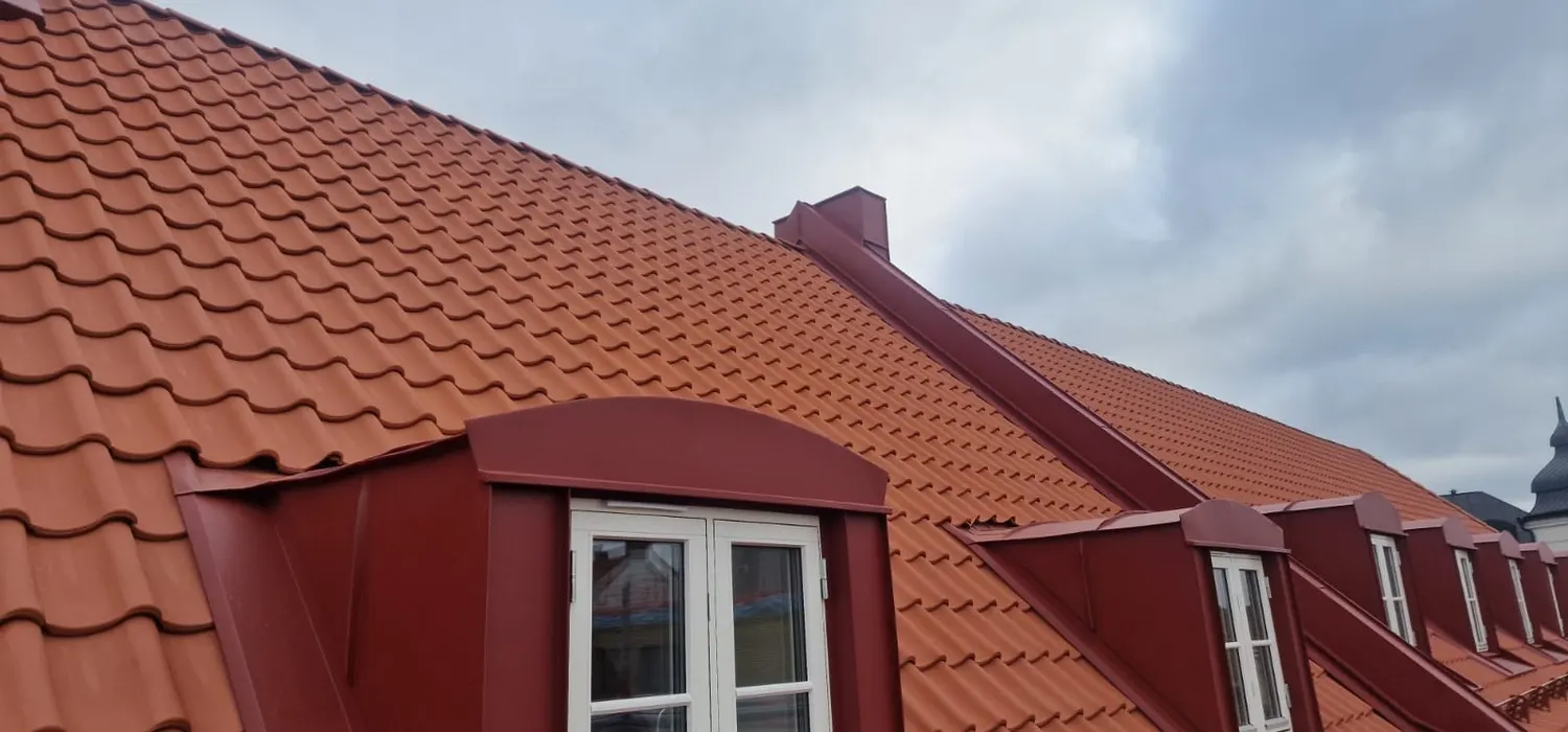 Kupa med rundad överdel i röd plåt mot tegelrött taktegel. Bild 4 av 6