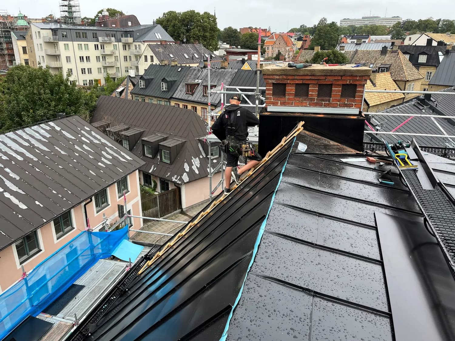 Plåtslagare på nocken där ny plåt möter det gamla taket. Bild 3 av 11