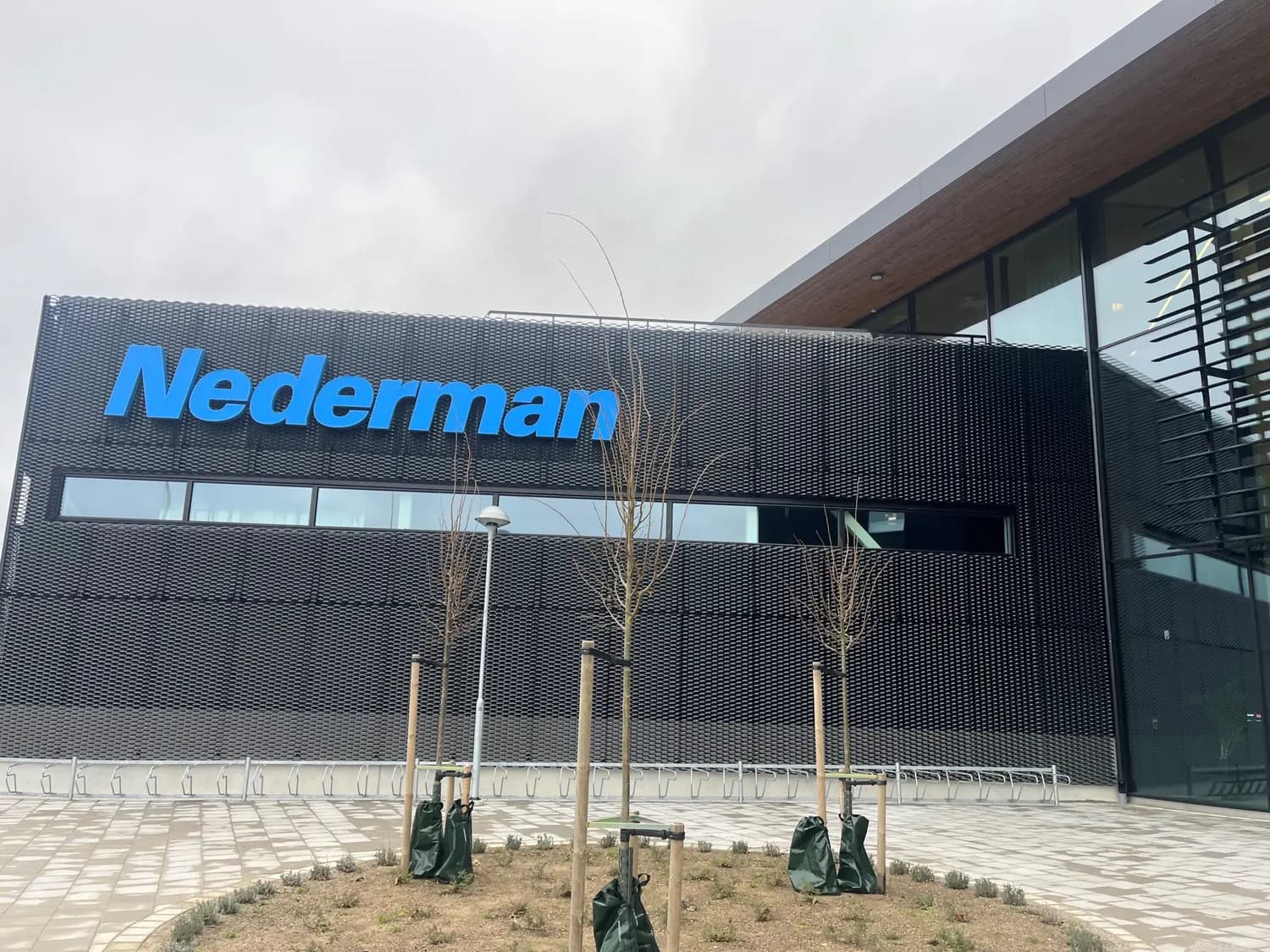 Fasaden med skylten, sedd över den nyanlagda entréplatsen. Bild 6 av 20