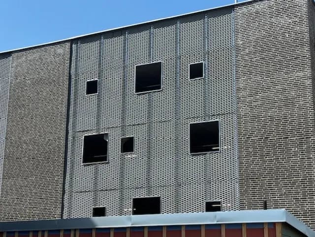 Fasad av sträckmetall med utsparade fönsteröppningar. Bild 11 av 13