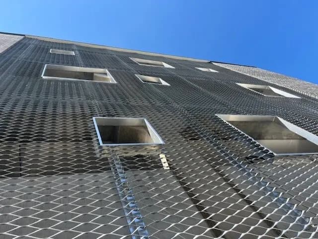 Sträckmetallens rutmönster i motljus, med öppningar för fönster. Bild 9 av 13