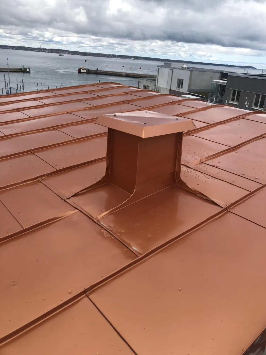 Ventilhuv inklädd i koppar mitt på det nylagda takfallet. Bild 16 av 23