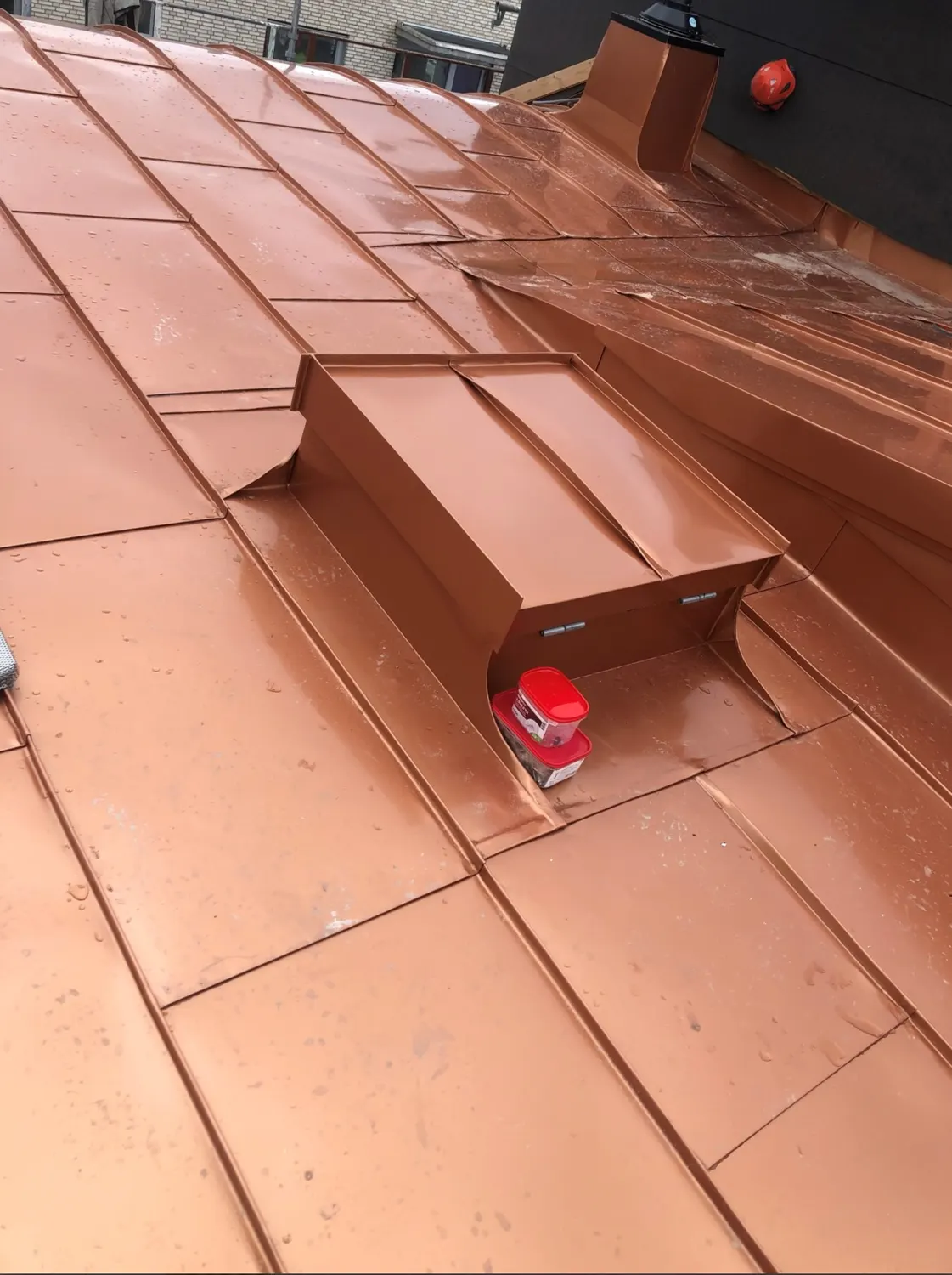 Kopparbeslag kring en genomföring på taket, verktyg bredvid. Bild 17 av 23