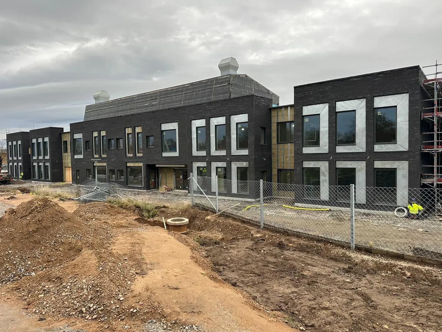 Byggnaden sedd över byggarbetsplatsen, fasaden i det närmaste klar. Bild 18 av 19