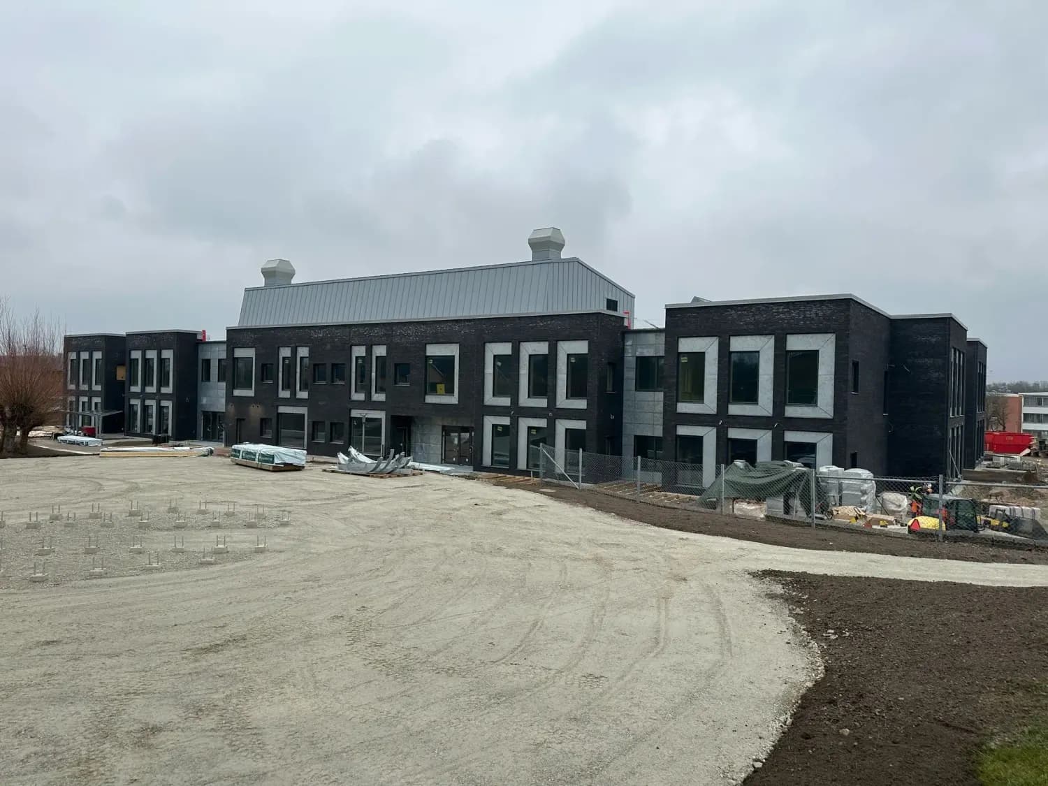Skolgården ännu obelagd, med hela byggnaden i bakgrunden. Bild 8 av 19