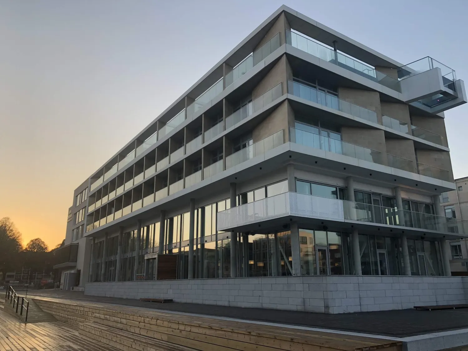 Kvarteret i kvällsljus, med indragna balkonger och glasräcken. Bild 1 av 18