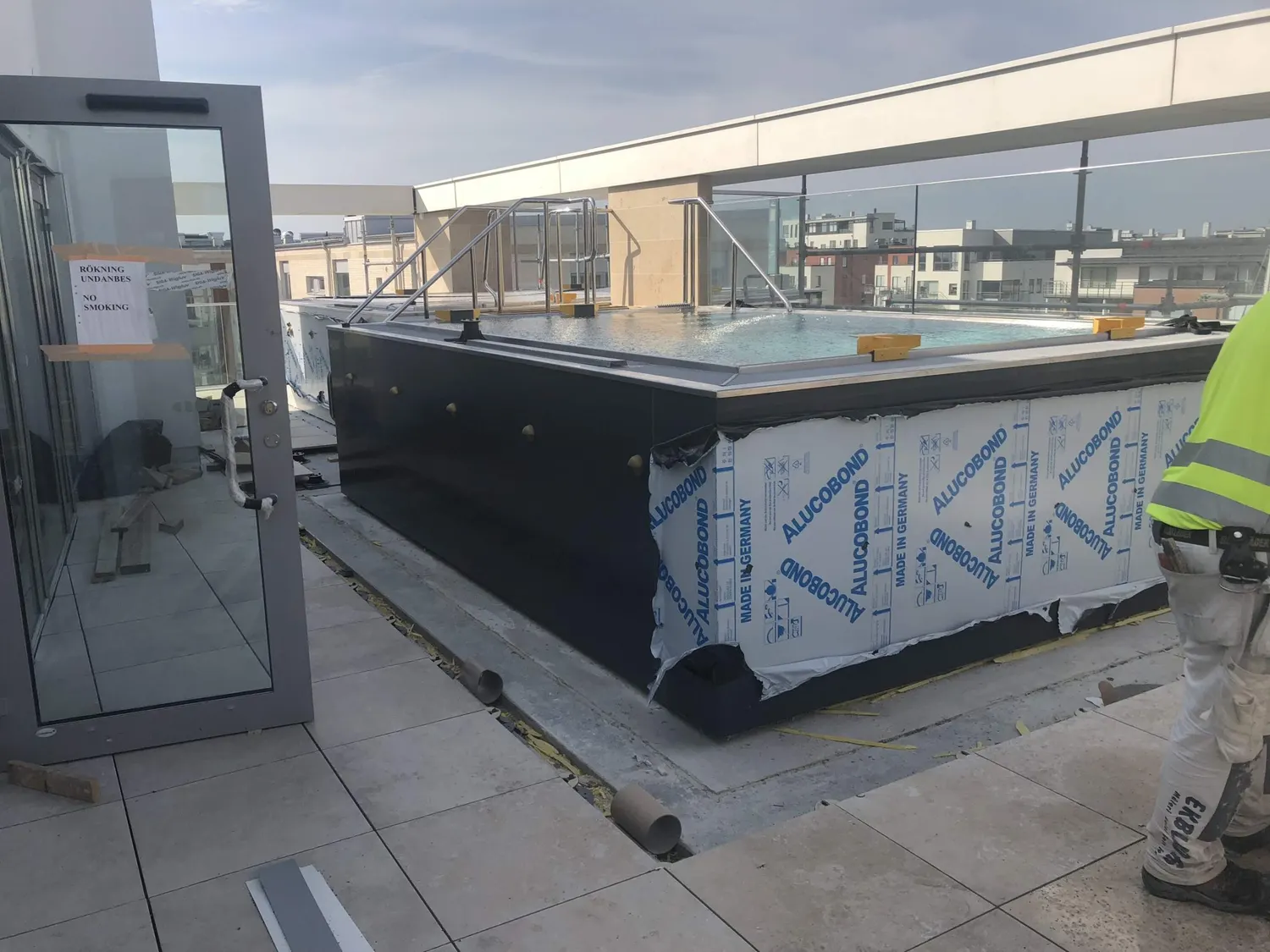 Takterrassens pool klädd i mörk plåt, staden bortom räcket. Bild 5 av 18