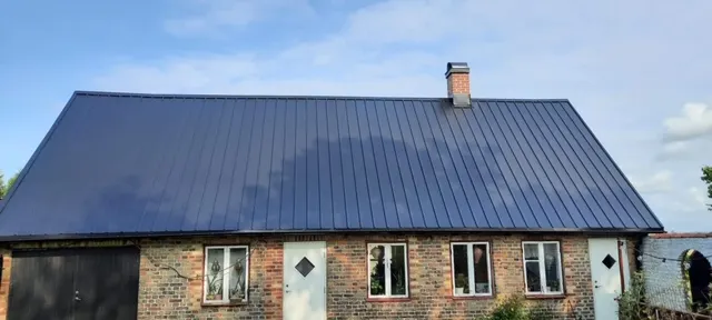 Tegellänga med nytt mörkblått plåttak och skorsten. Bild 61 av 62