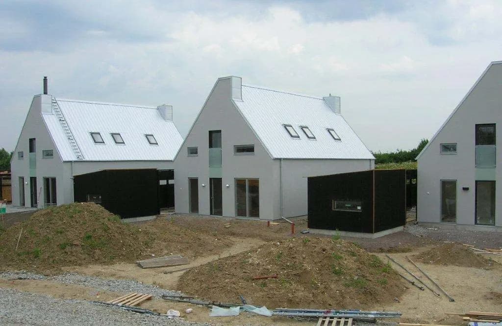 Nybyggd villa med ljust plåttak och svarta uthuslängor. Bild 49 av 62