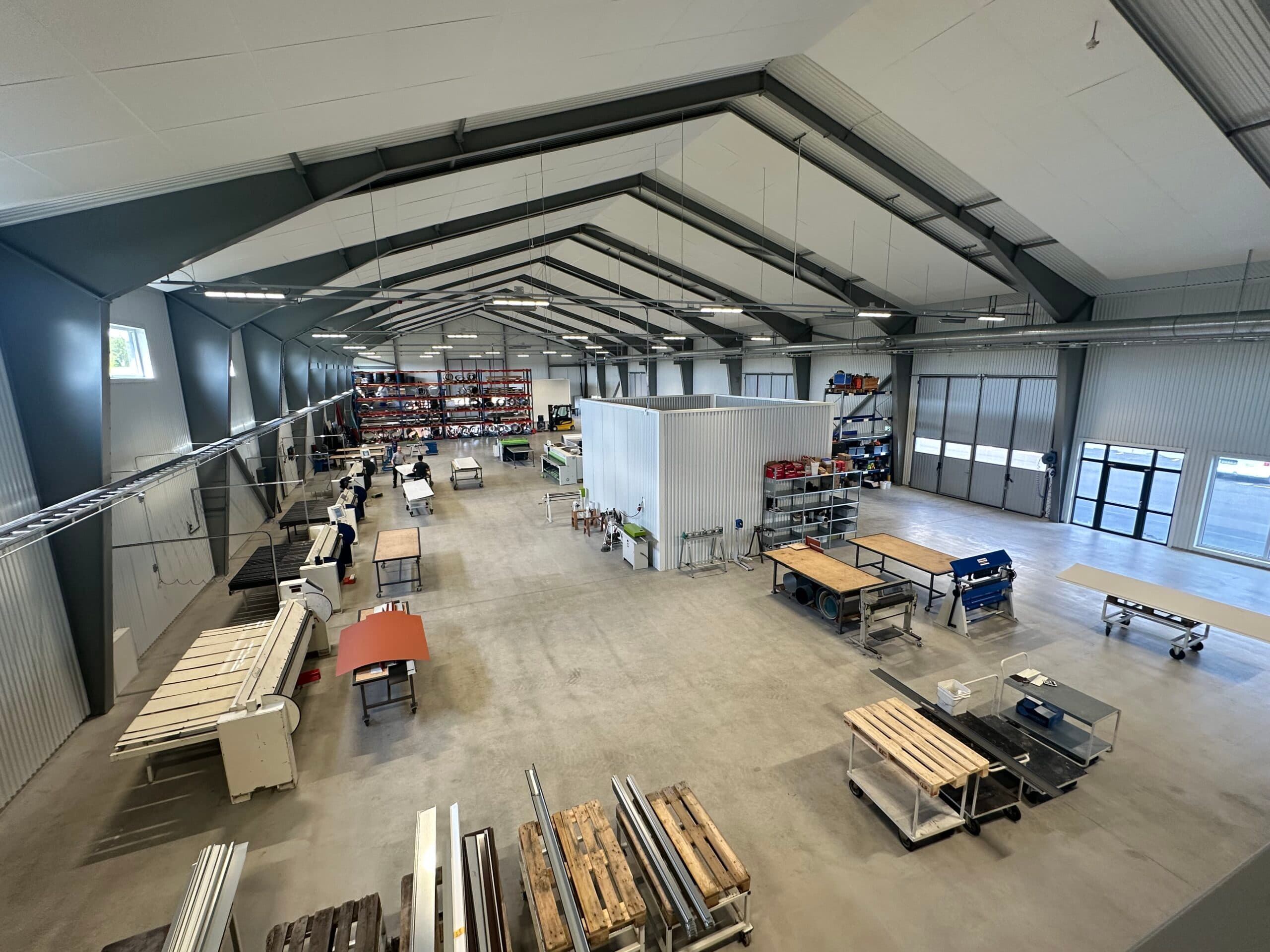 Verkstadshallen i Ekeby sedd från entresolplanet, med arbetsbord och plåt på pall
